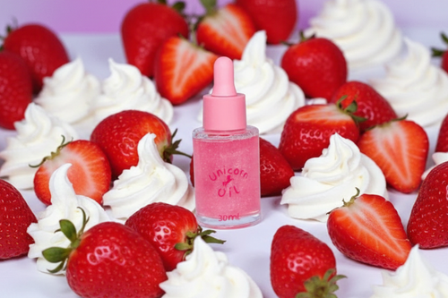 Strawberries & Cream 30ml scented nail serum surrounded by fresh cut strawberries and whipped cream