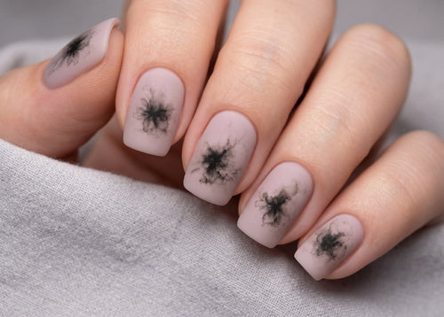Nails with black abstract designs on a light gray background
