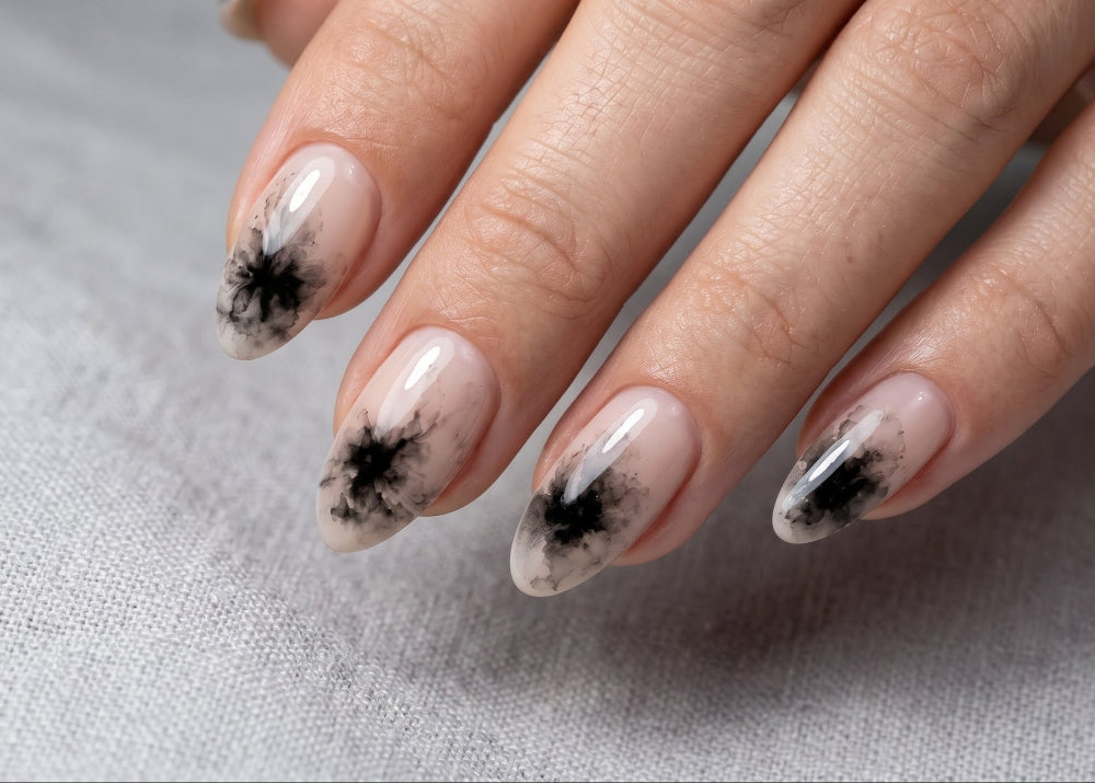 Close-up of a hand with nails featuring black floral designs on a light gray background