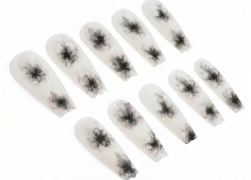 Set of white false nails with black spider designs on a white background