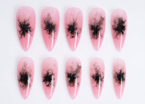 Pink nail art with black abstract designs on a white background