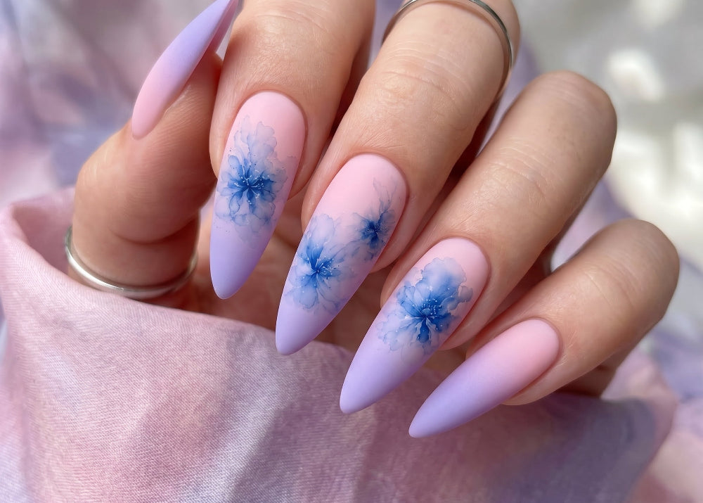 Nails with blue floral design on a light pink background