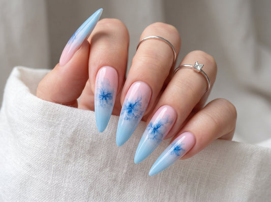 Nails with blue floral design and gradient color on a neutral background