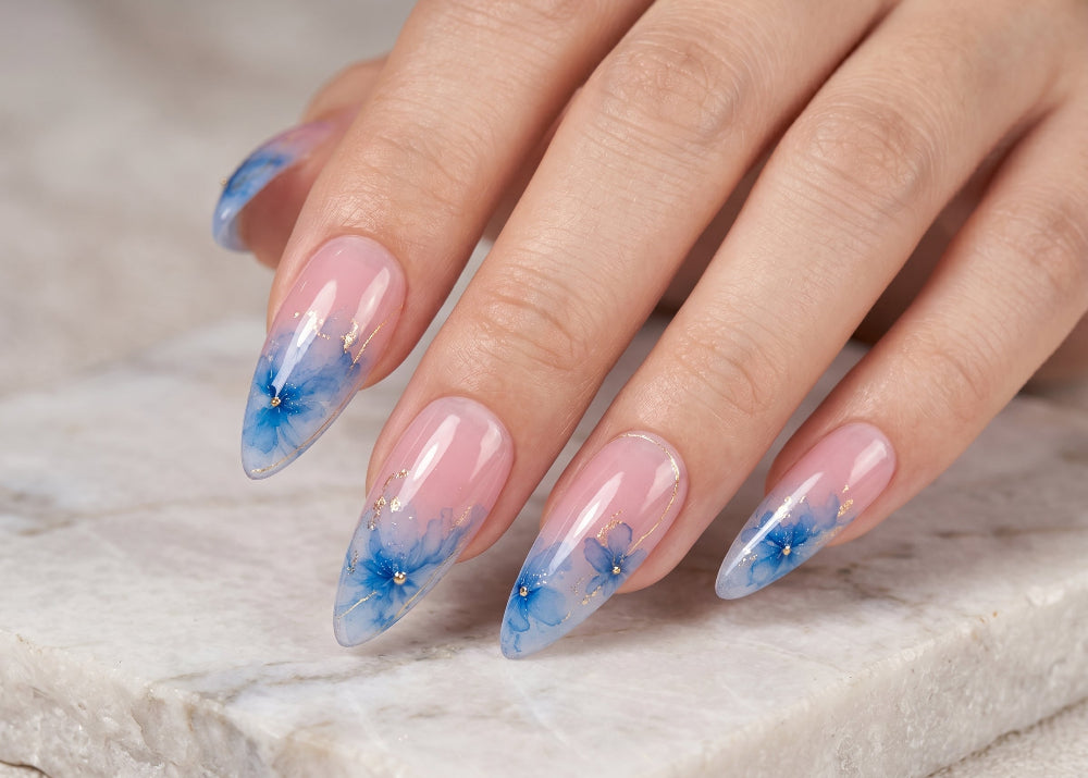 Hand with blue floral nail design on a marble surface