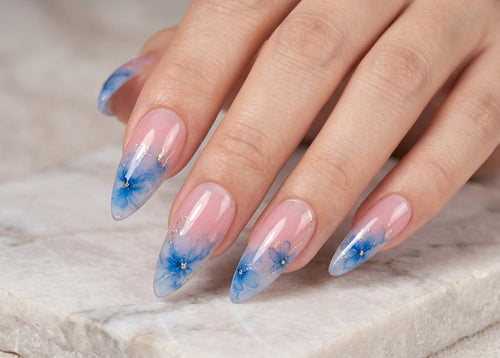 Hand with blue floral nail design on a marble surface