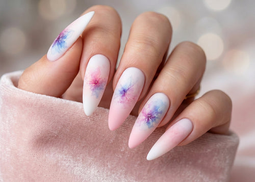Nails with watercolor floral design held by a person wearing a pink sweater.