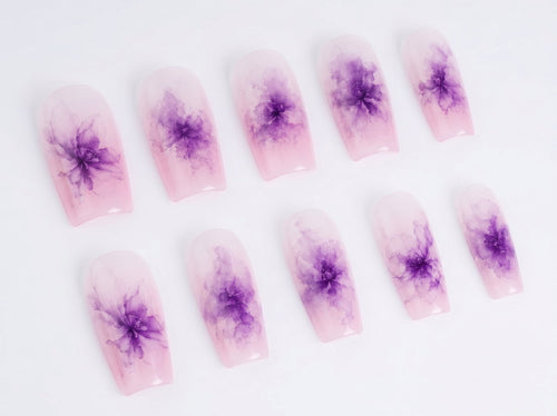 Nail art with purple flower designs on a white background