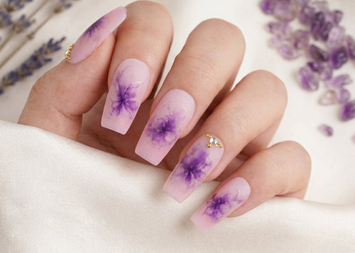 Nails with purple floral design on a white background