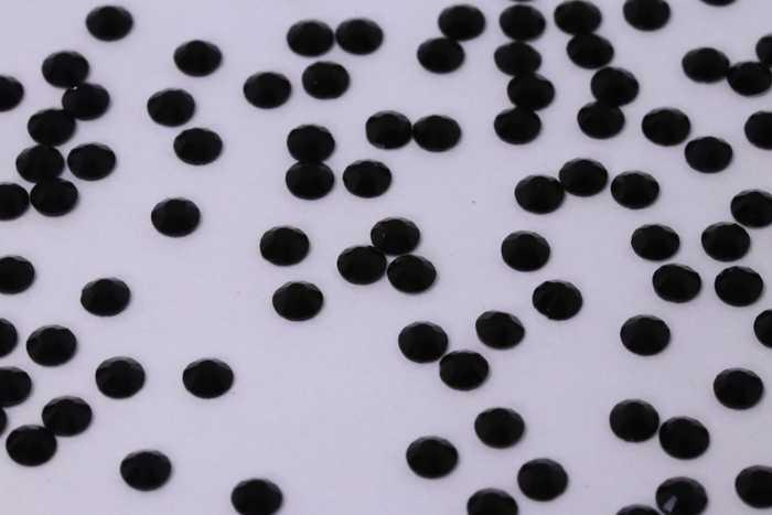 Close-up of Jet SS4 black glass rhinestones on a professional nail art palette.