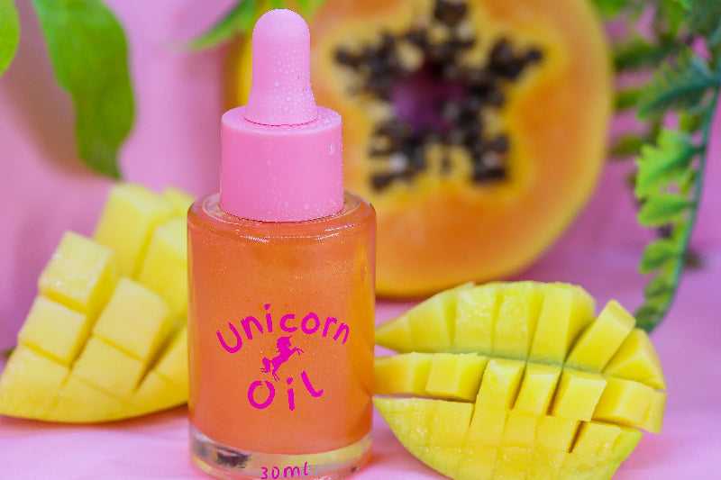 Mango & Guava Unicorn Cuticle Oil in large 30ml luxury dropper bottle with pink lid. Product is pictured next to fresh cut mangos and guavas