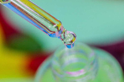A detailed macro image of Killer Python Unicorn Cuticle Oil - showing sparkle in dropper, dripping into bottle